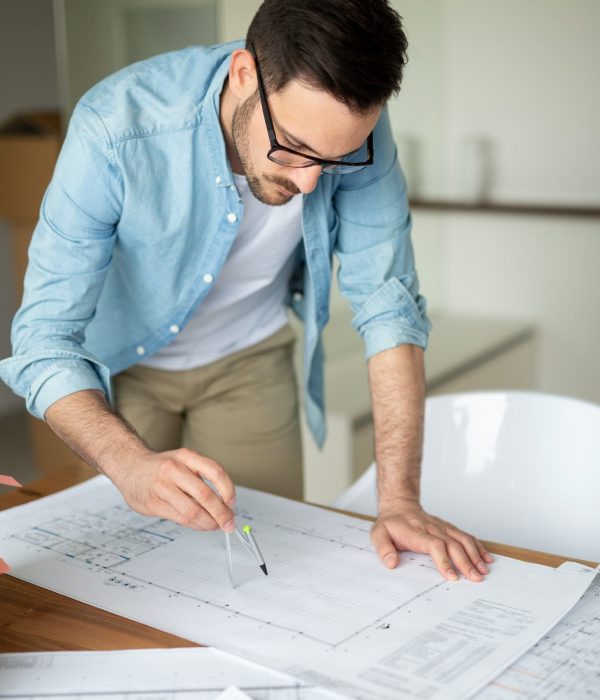 Portrait of adult architect working on plans and blueprints